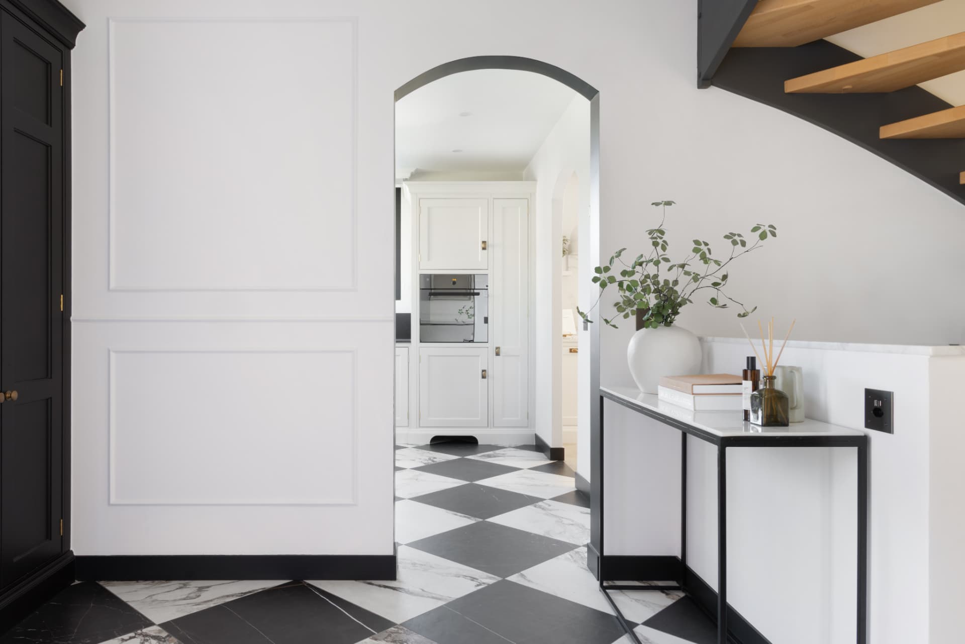 Entrance hall with chequerboard marble floor, panelled walls and an arched opening to the kitchen