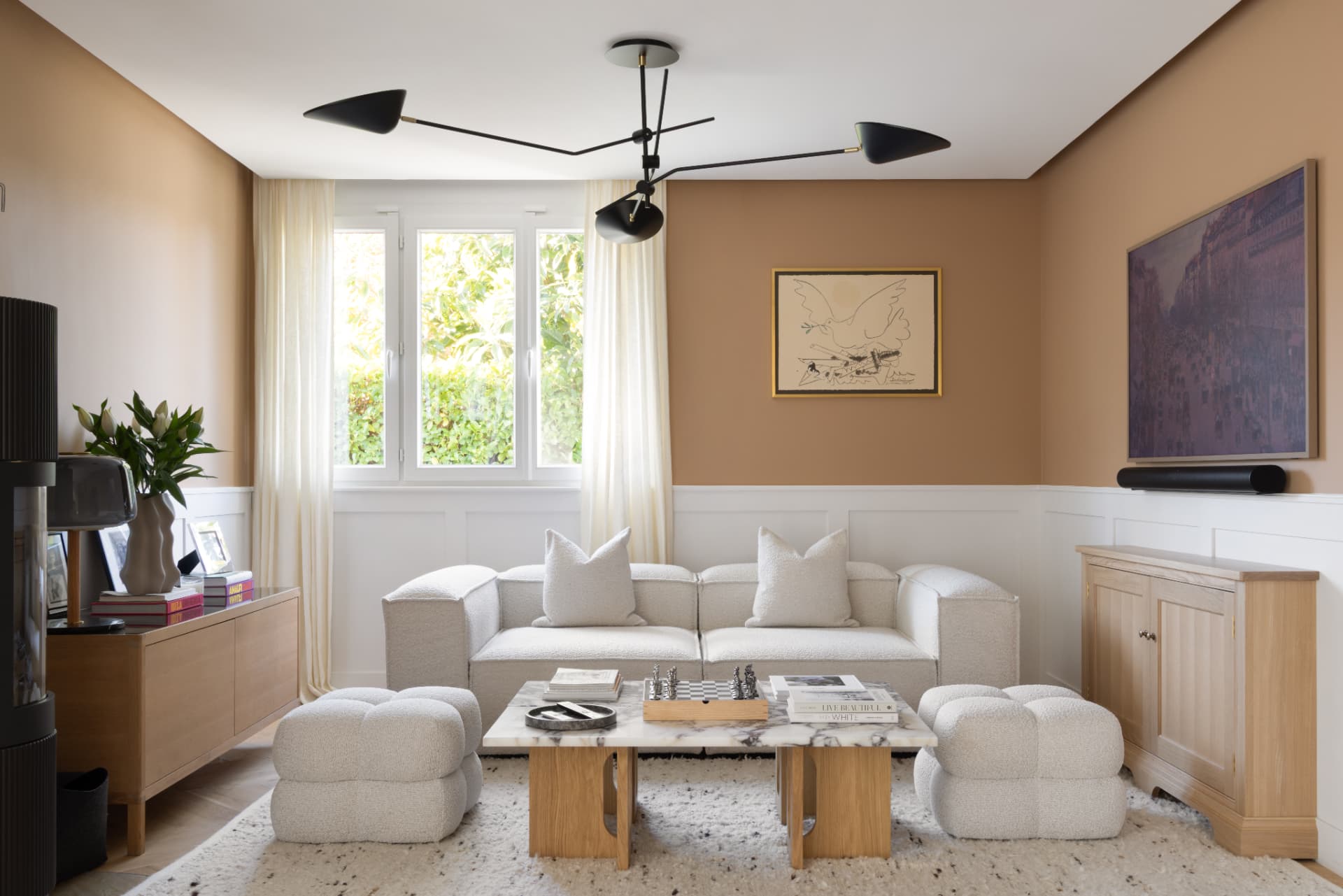 Lake Geneva House — living room with warm tan walls, bouclé sofa, marble coffee table and a sculptural black ceiling light